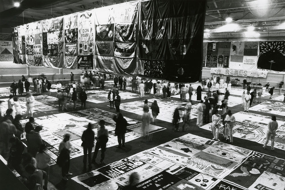 archival photo of AIDS quilt laid out with people walking around it