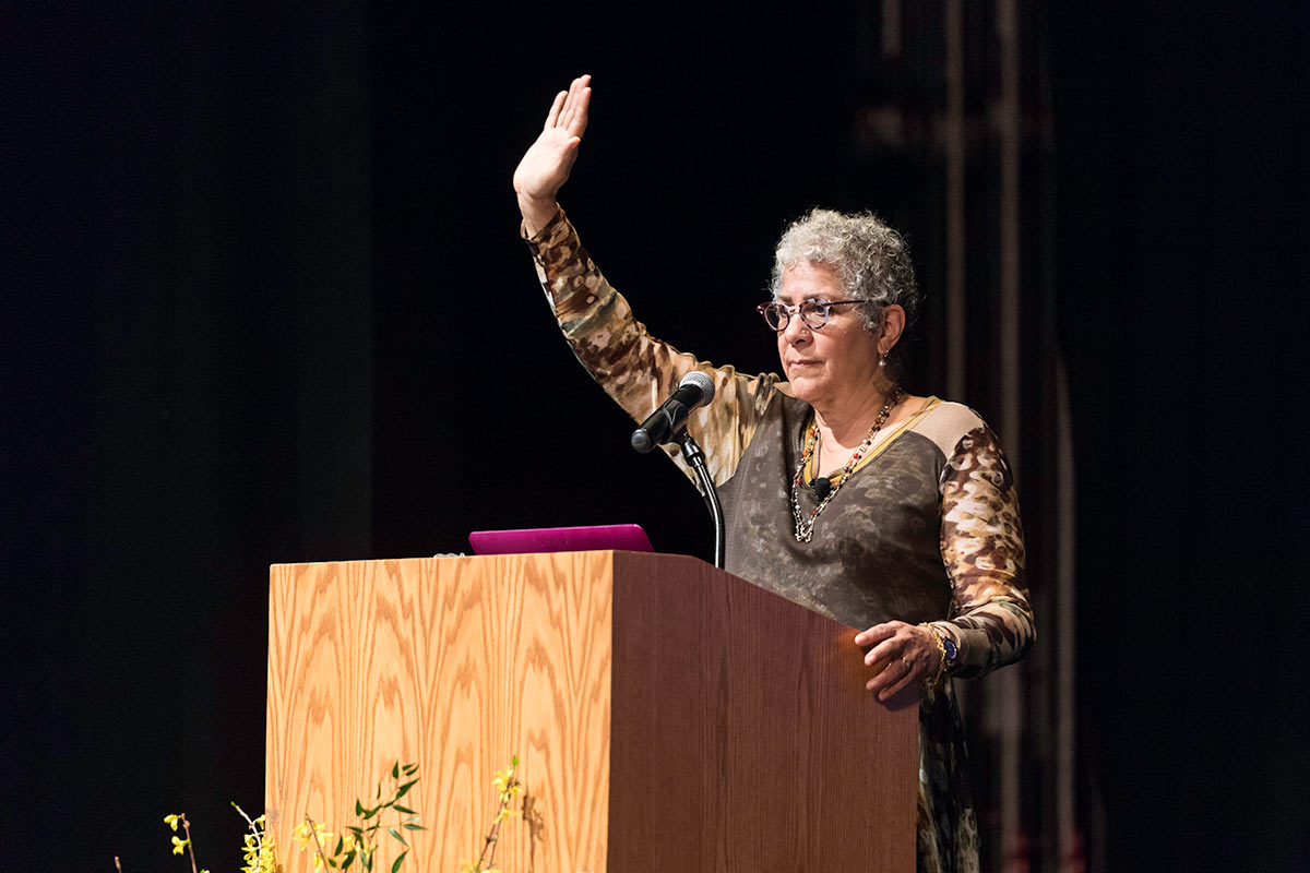 woman at podium with her arm raised