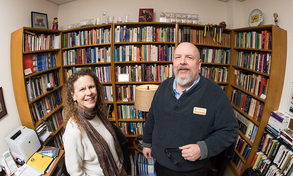 Feature image man and woman smile in front of bookshelves and baseballs