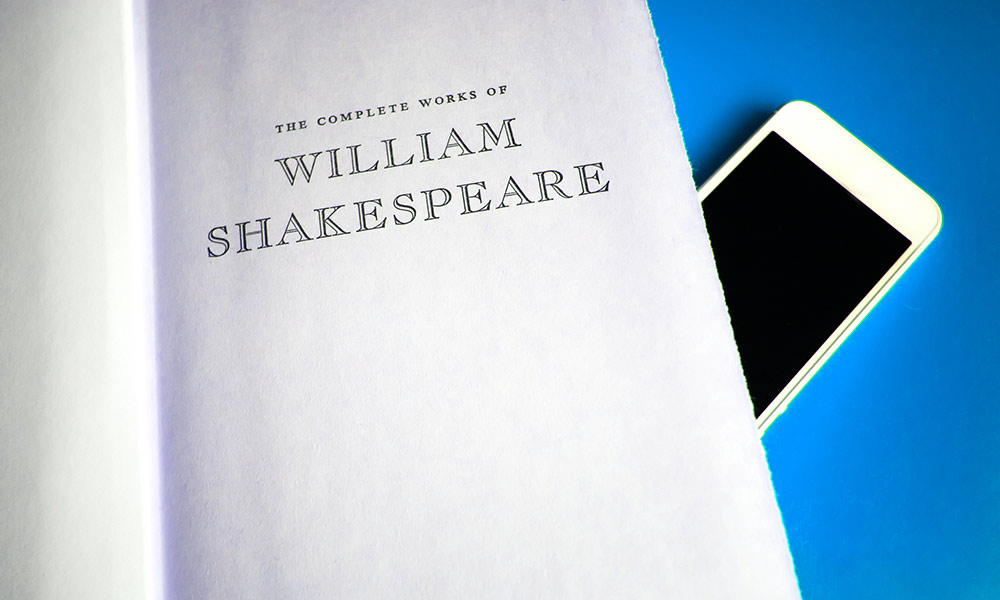 cell phone sitting on a book of William Shakespeare