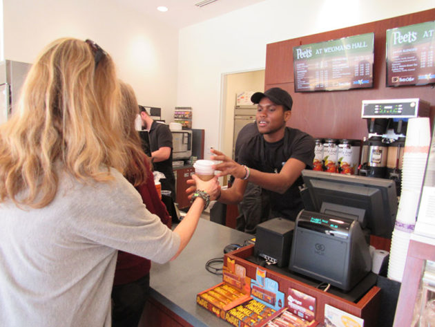 coffee shop with worker handing coffee to a customer
