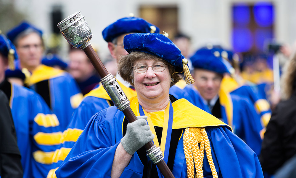 woman in graduation robes carrying a mace