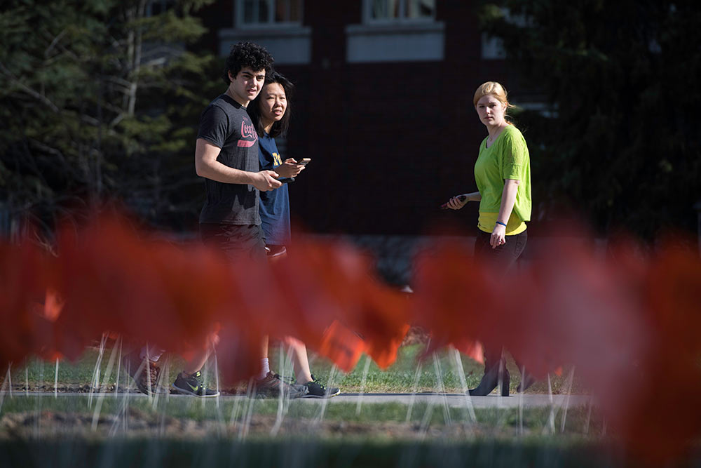 students walk by small orange flags