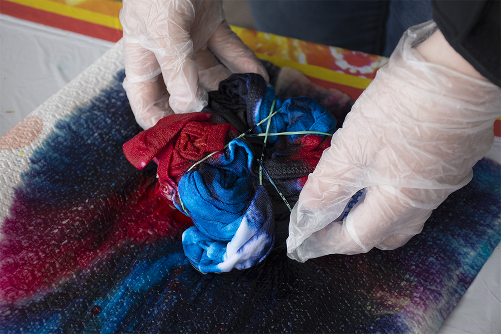 gloved hands hnadling a rubber banded t-shirt