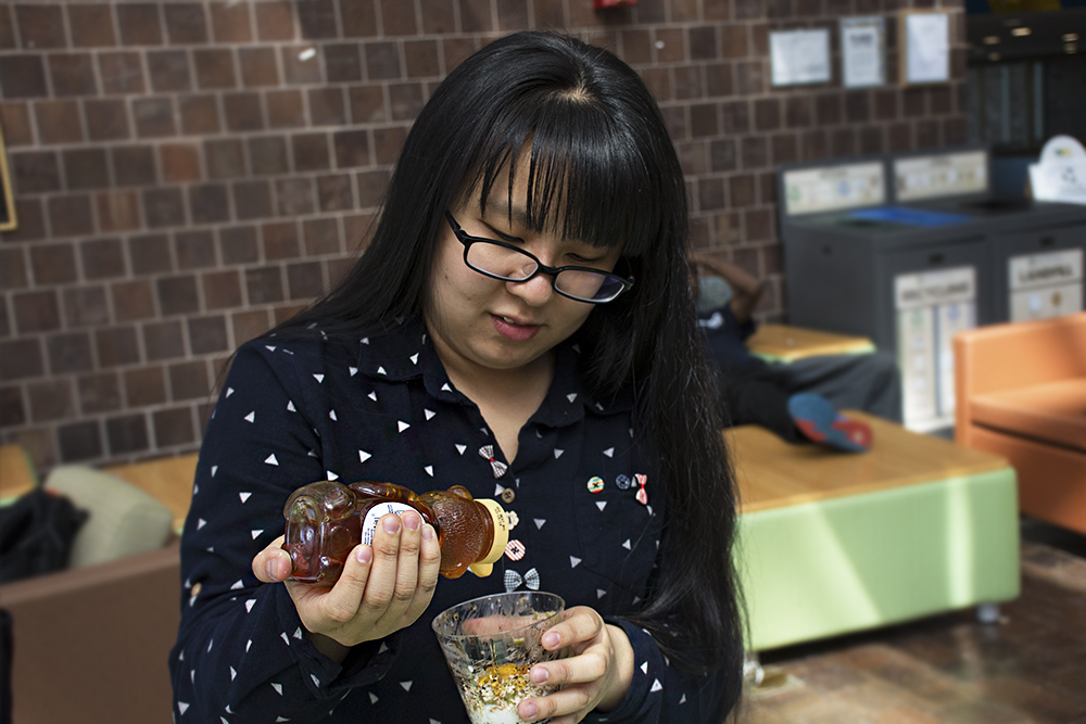 woman pouring honey into a cup