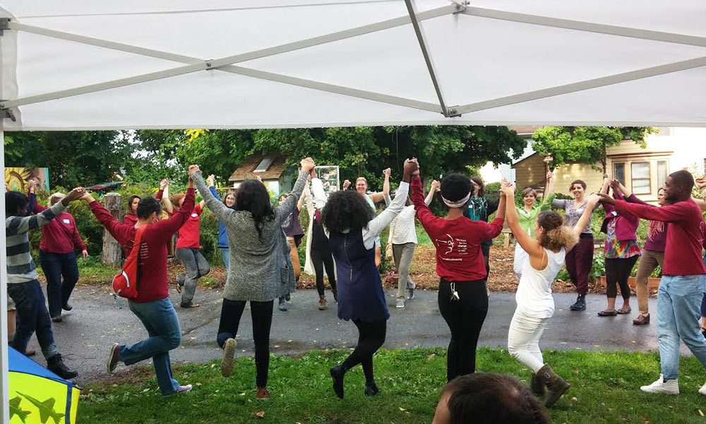 Feature image people dancing with arms upraised under a tent