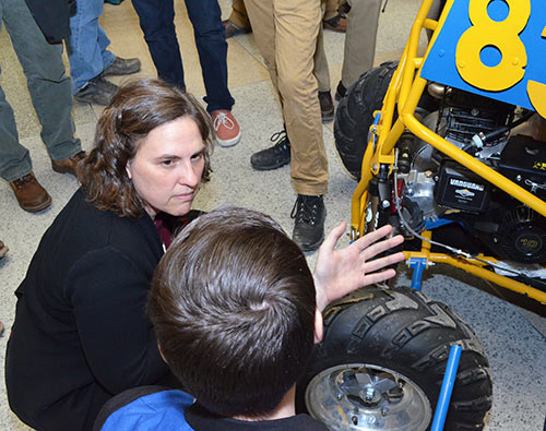 woman and student sitting next to baja car