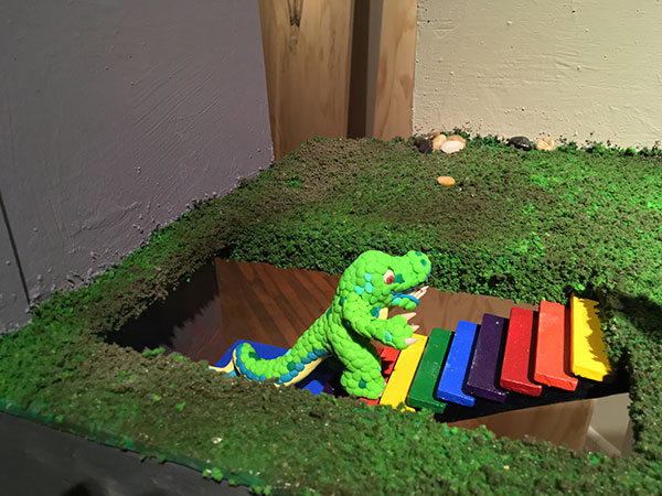 clay model of dinosaur walking up steps