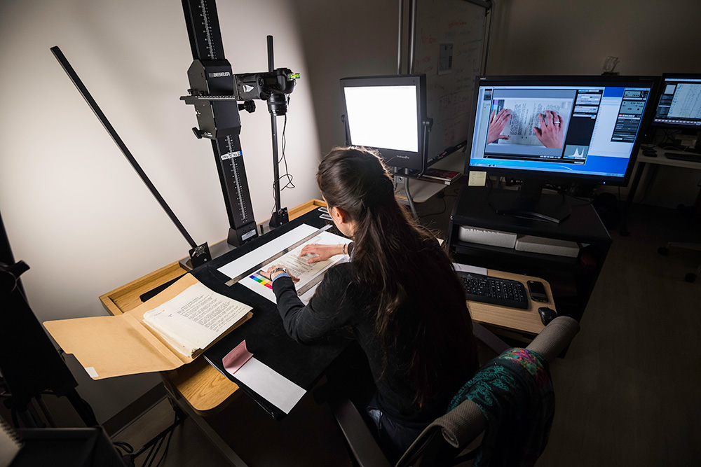 student in a dark lab, with a document under a camera