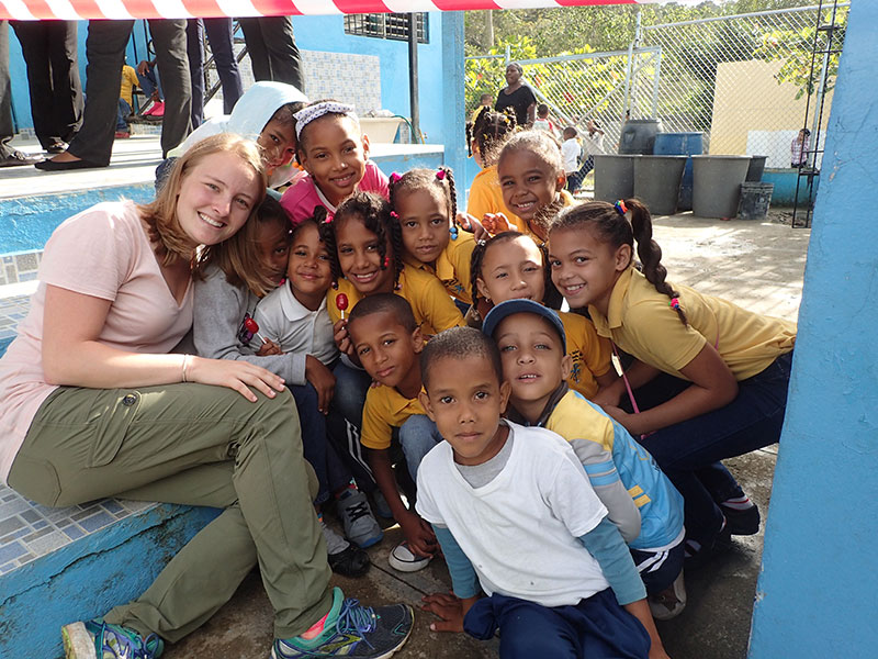 student poses for a photo with a large group of kids