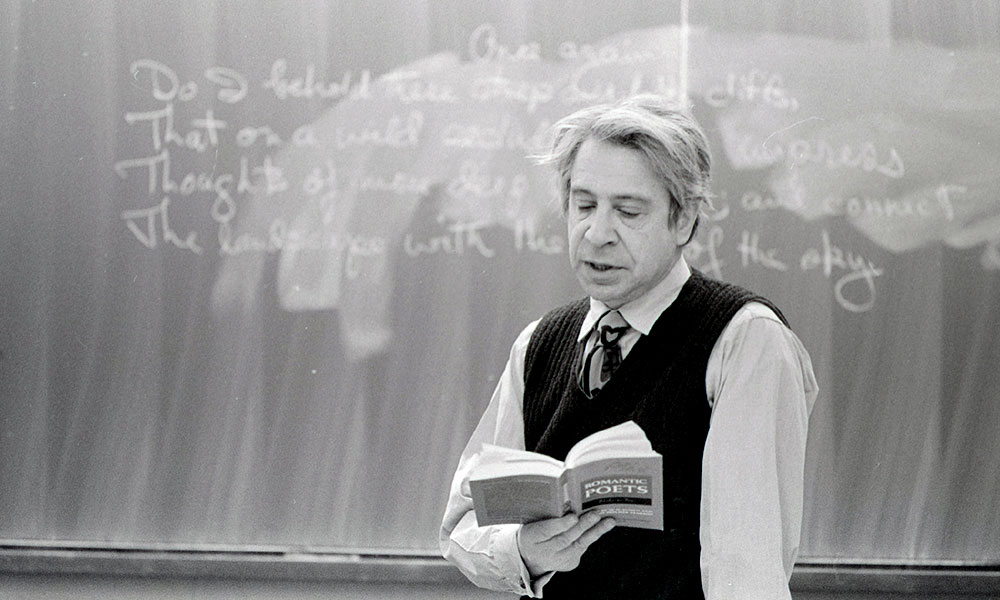 Feature image professor reading poetry in front of blackboard