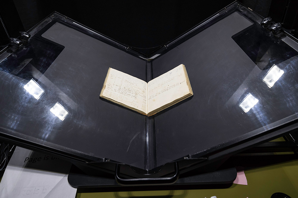 Feature image old book on a black stand, getting ready to be scanned