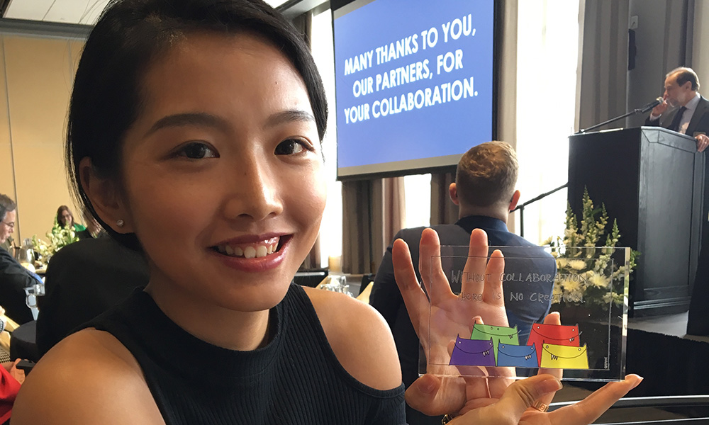 Feature image student smiling and holding up award