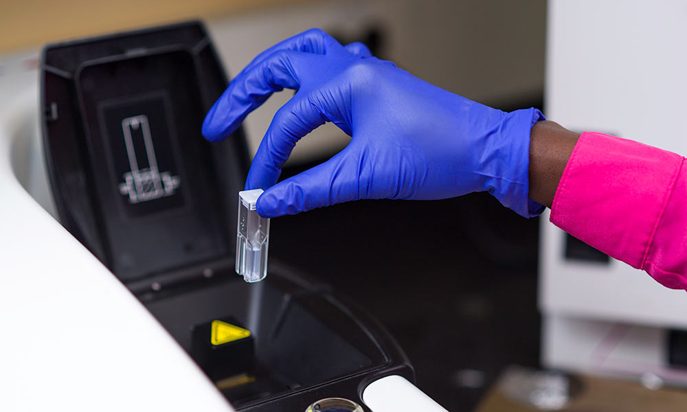 Feature image gloved hand holding vial