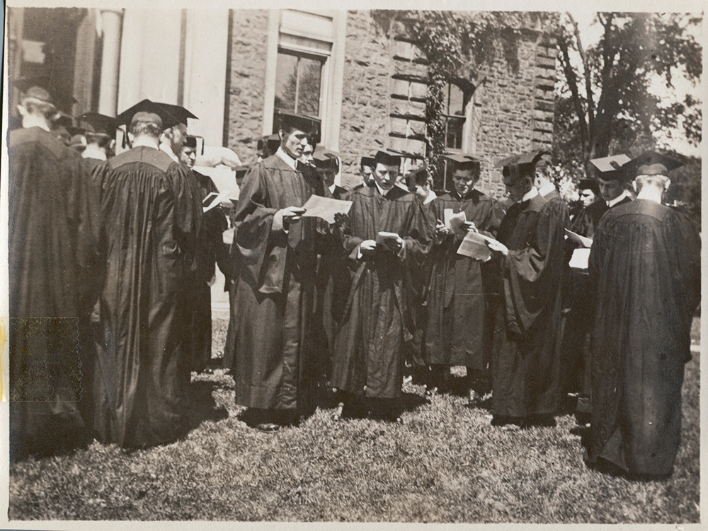 men in graduation robes looking at papers