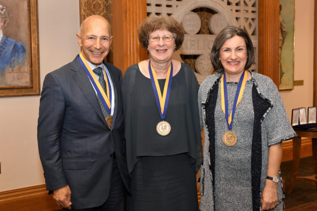 three people wearing medals pose for a portrait