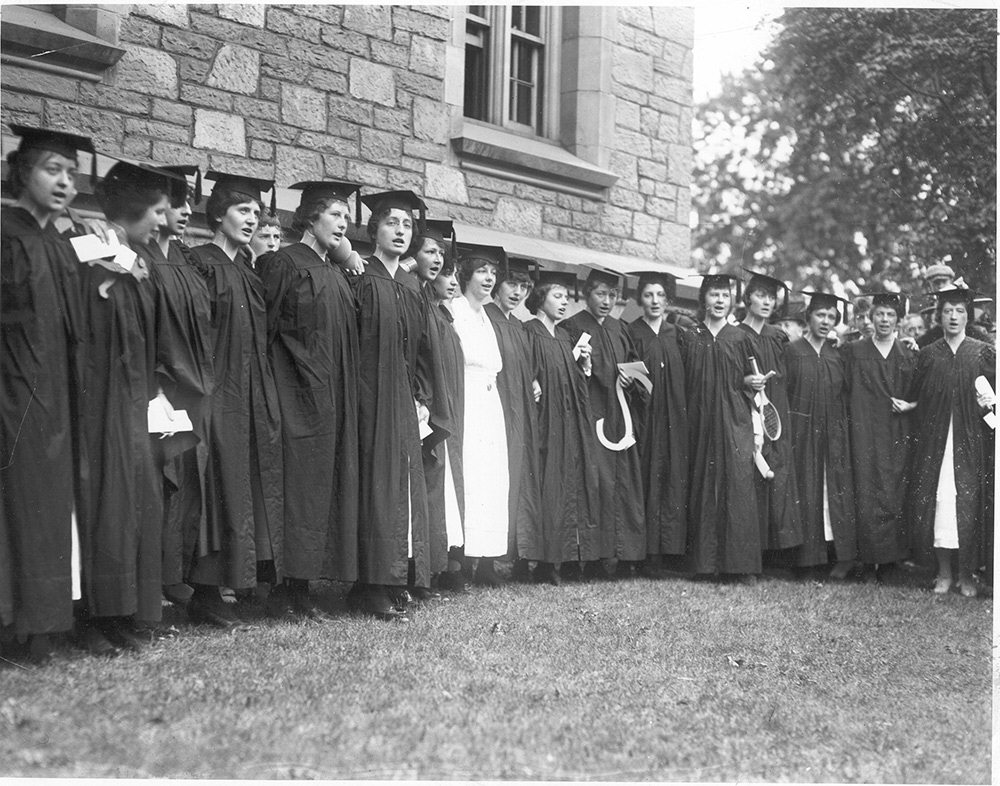 women in graduation robes singing