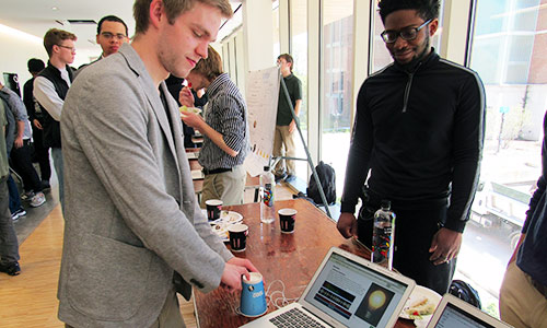 two students standing and looking at a laptop