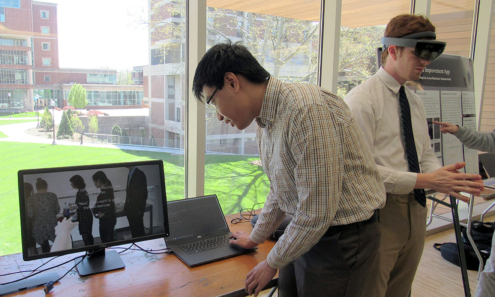 one student looking at a laptop, another wearing virtual reality goggles