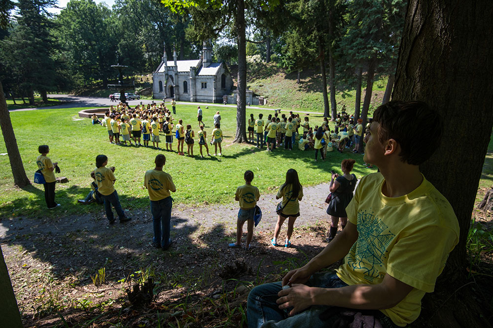 large group of students listening to a professor speak in a cemetary
