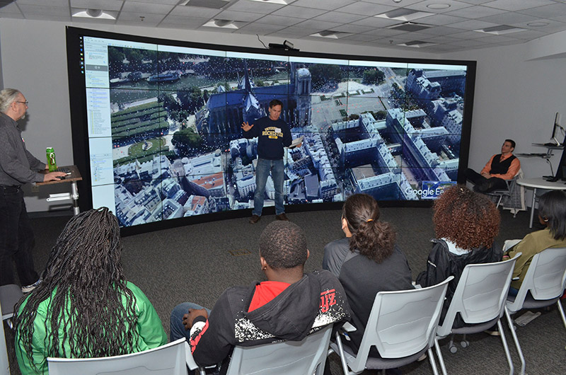 row of students in front of large computer screen