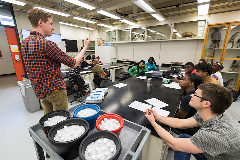 teacher holds up vials of fruit fly species