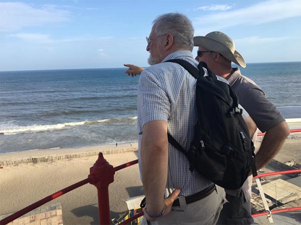 Tow men poitning at beach from a lighhouse