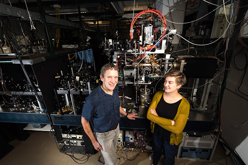 student and professor in lab surrounded by optics