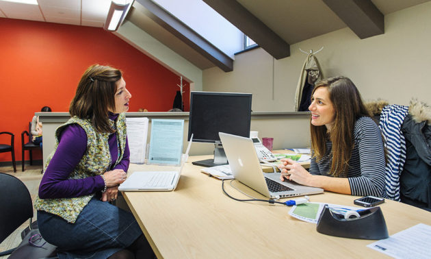 two women conversing while sitting at a conference table