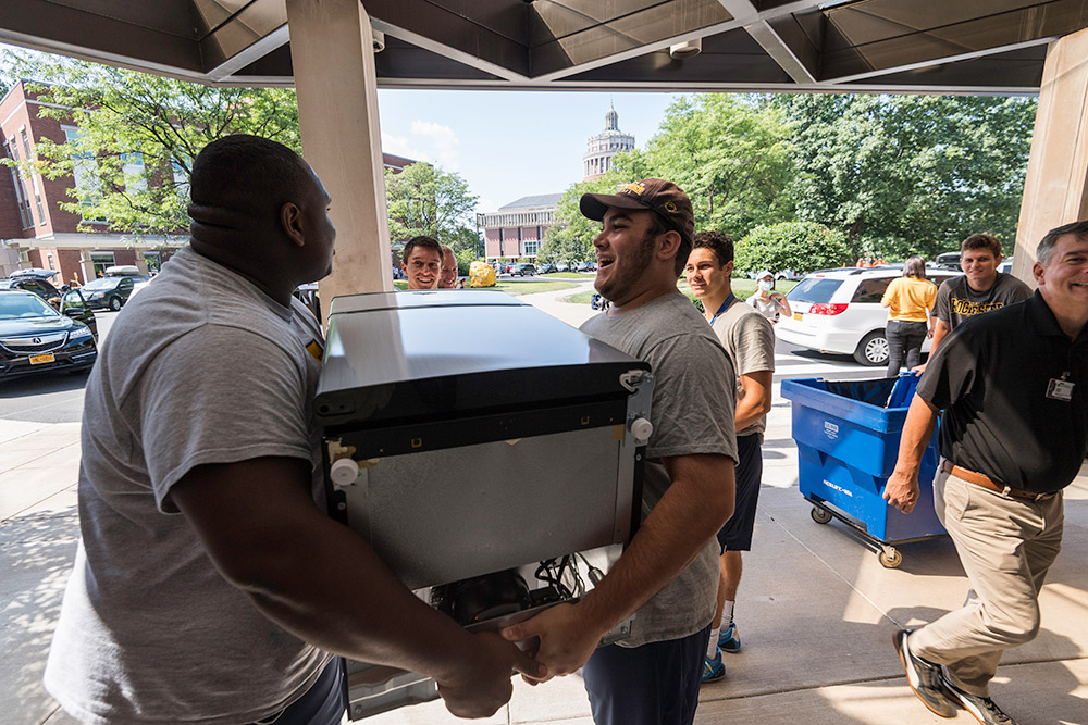 two students carrying a refrigerator