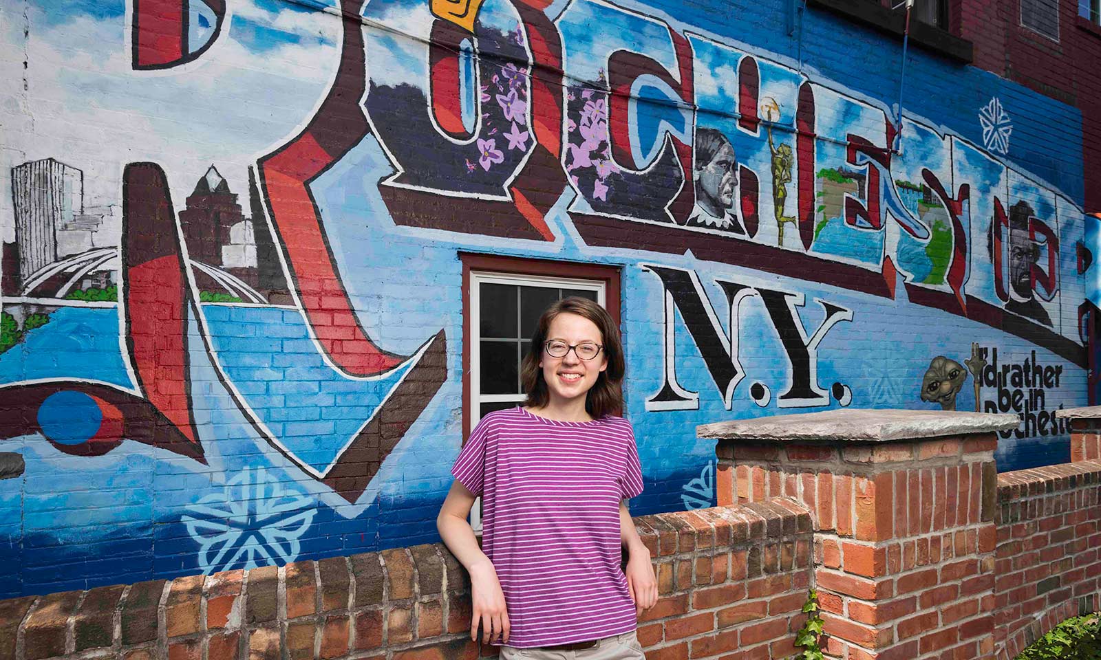 Feature image students stands in front of wall mural painted with the words ROCHESTER, NY
