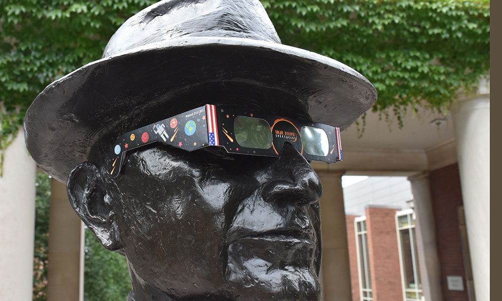 statue of George Eastman wearing solar eclipse glasses