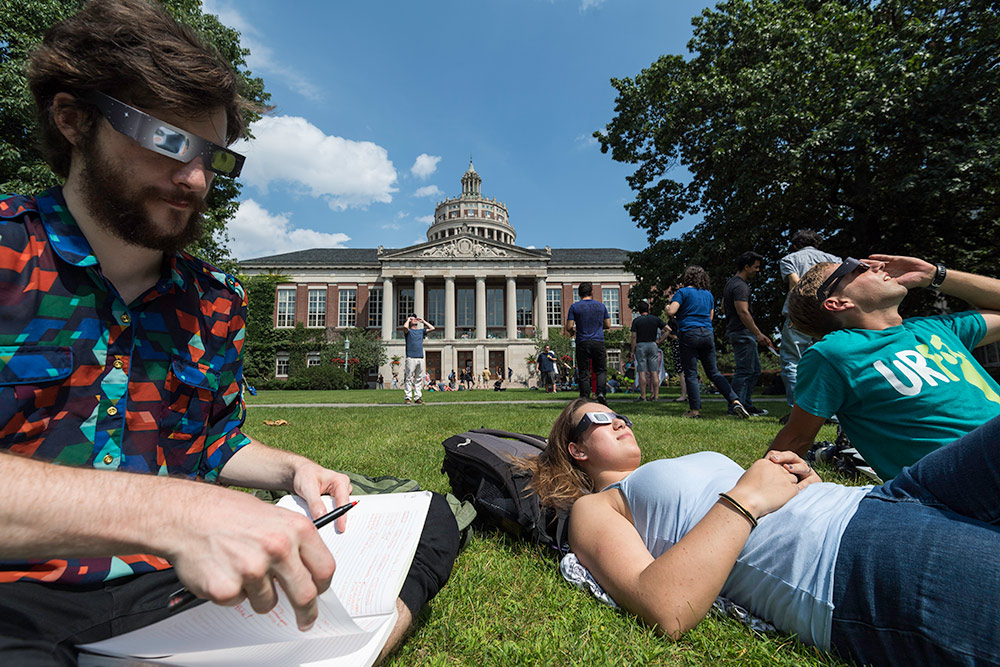 three people sitting on the quad, watching the eclipse