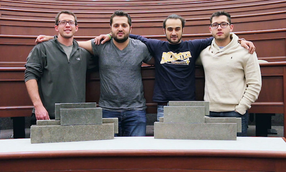 Feature image four team members pose behind a table covered in bricks
