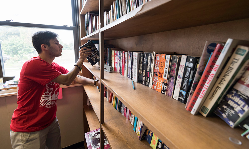 student placing books on a shelf