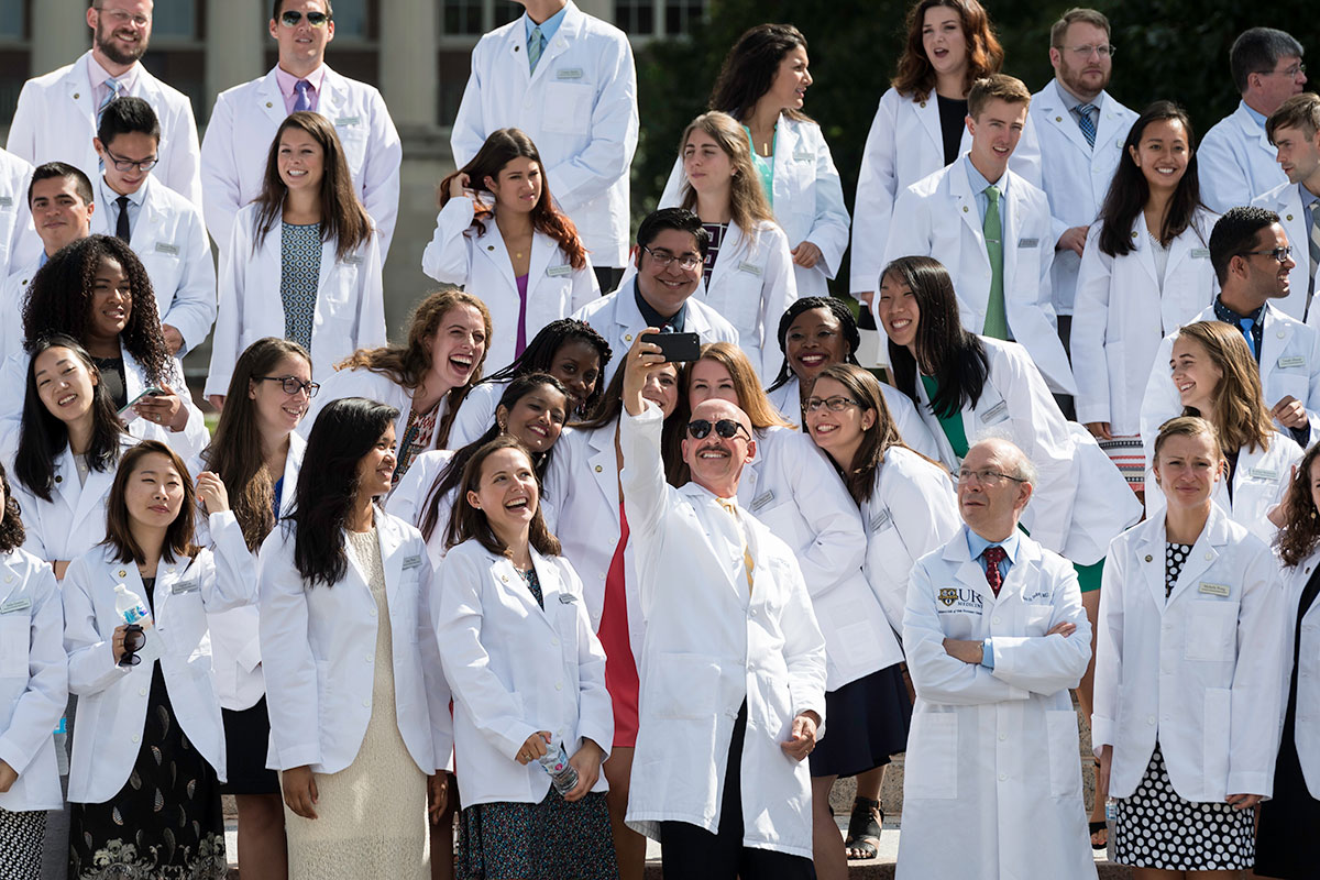 students taking selfie, all wearing white doctors coats