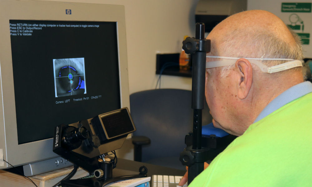 patient rests his chin and forehead on a device while looking at a screen