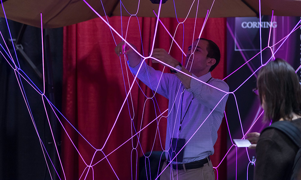 man surrounded by thin, colorful strands of light
