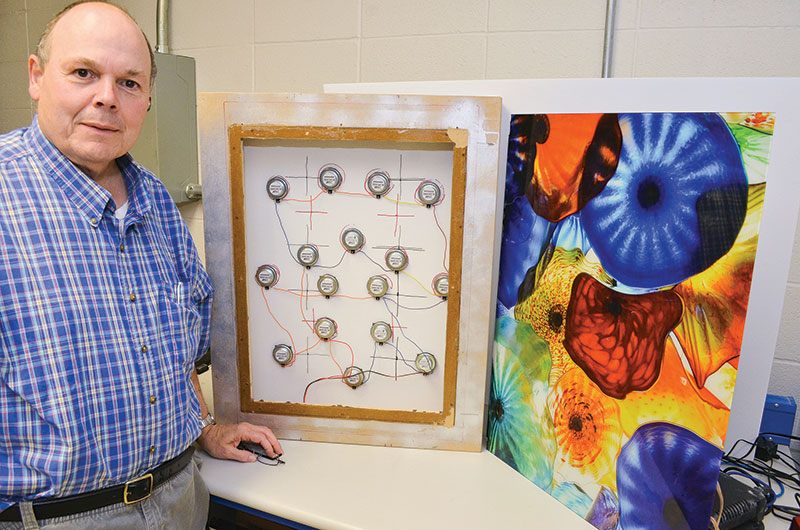 Mark Bocko standing next to a prototype of a flat panel speaker made to look like a painting