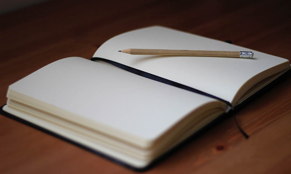 Feature image A pencil lies atop an open, blank book