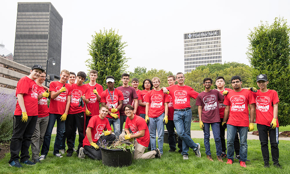 students wearing red t-shirts and work gloves near city buildings