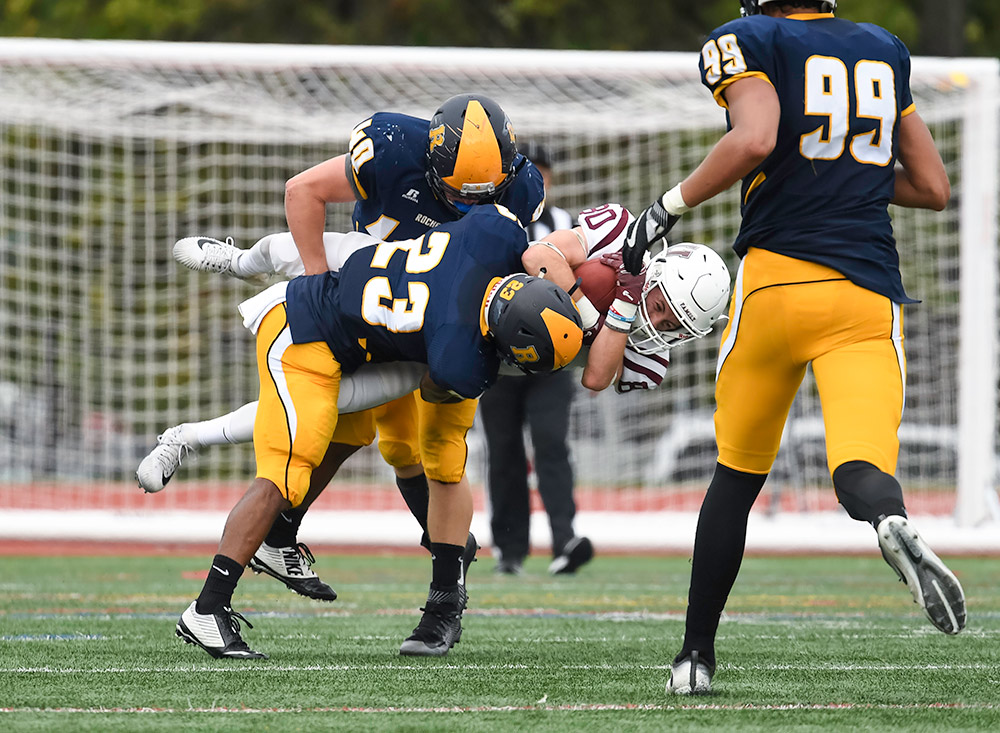 two football players tackle another football player