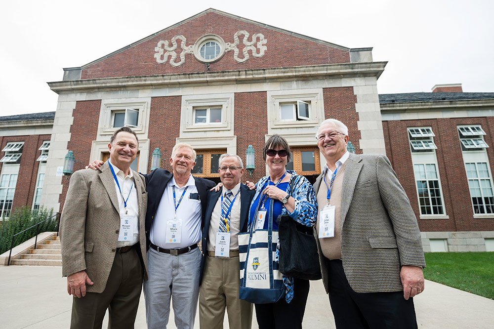 five people posing for a photo outside a building