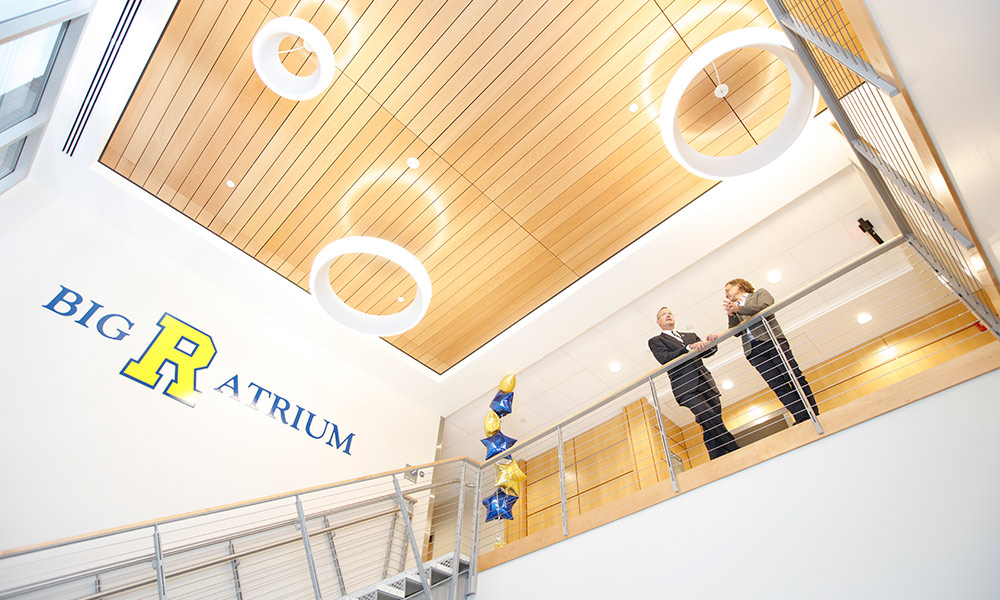 two people standing on a balcony next to a sign that reads BIG R ATRIUM