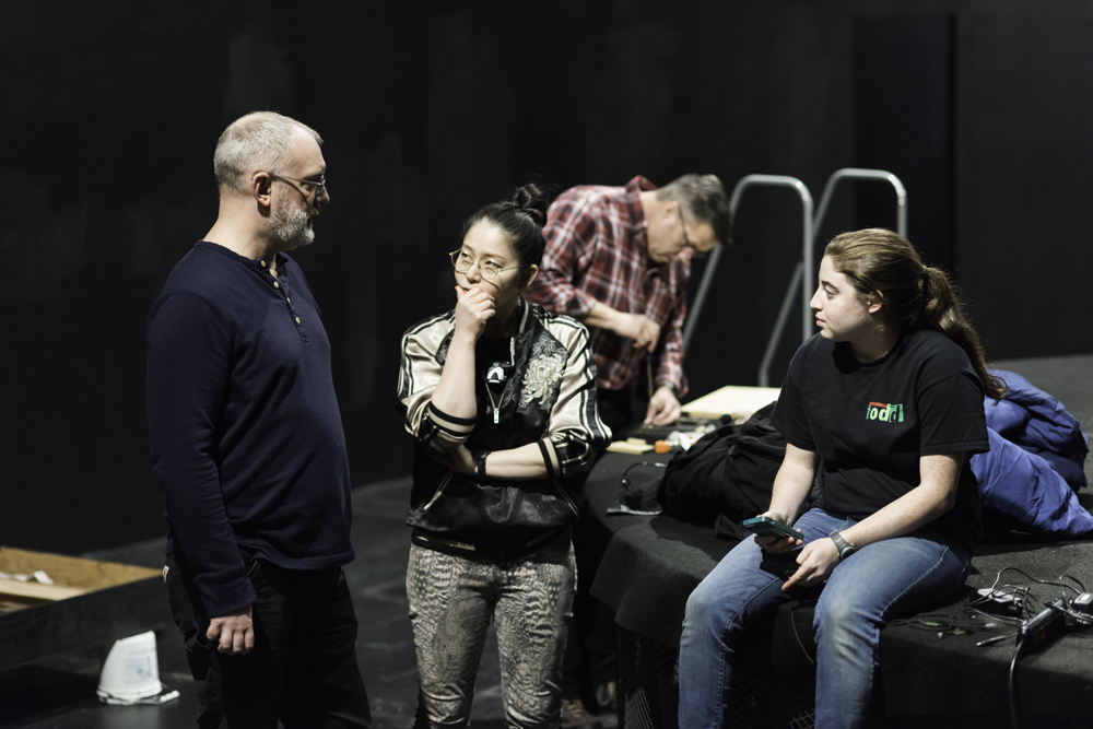 two students sitting on the stage and speaking with Ken Rus Schmoll