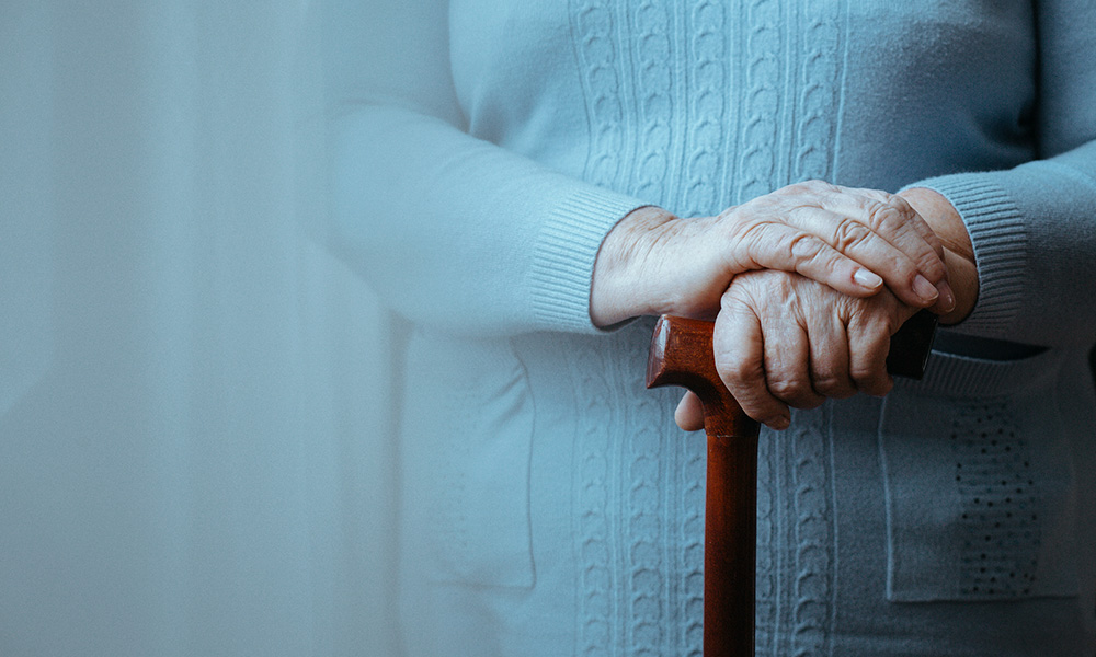 Elderly woman's hands grasping cane.