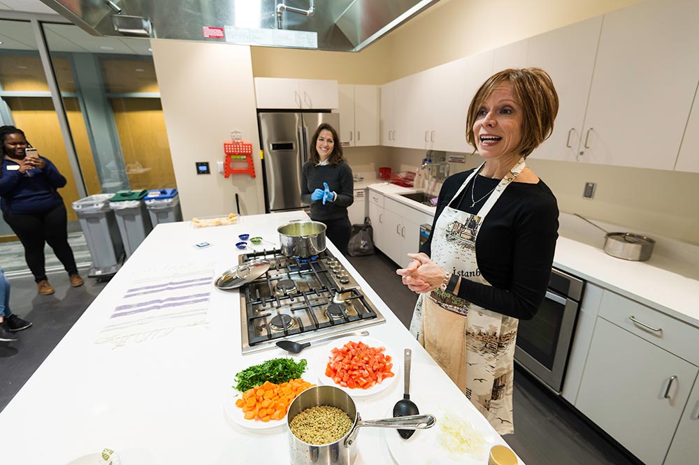 two women in a community kitchen, talking about the recipe they are making