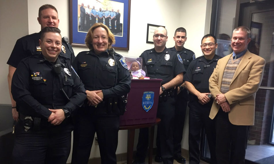 public safety officers smile and stand with a donation box