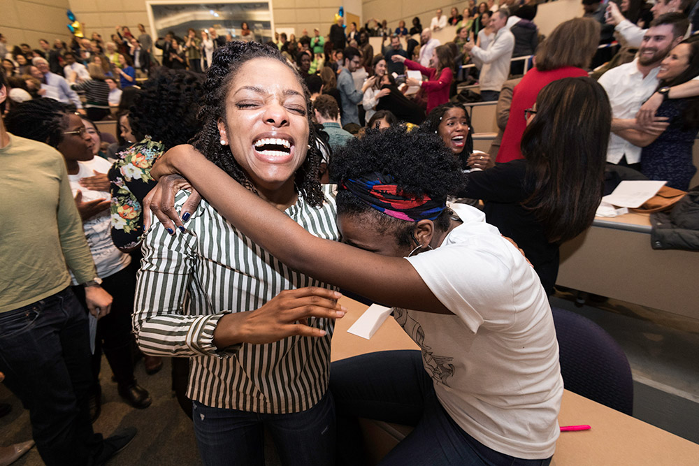 two students hugging, crying, celebrating