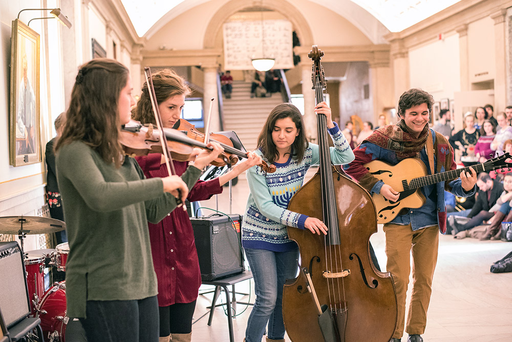 Feature image group of student musicians performing in crowded, decorated hall